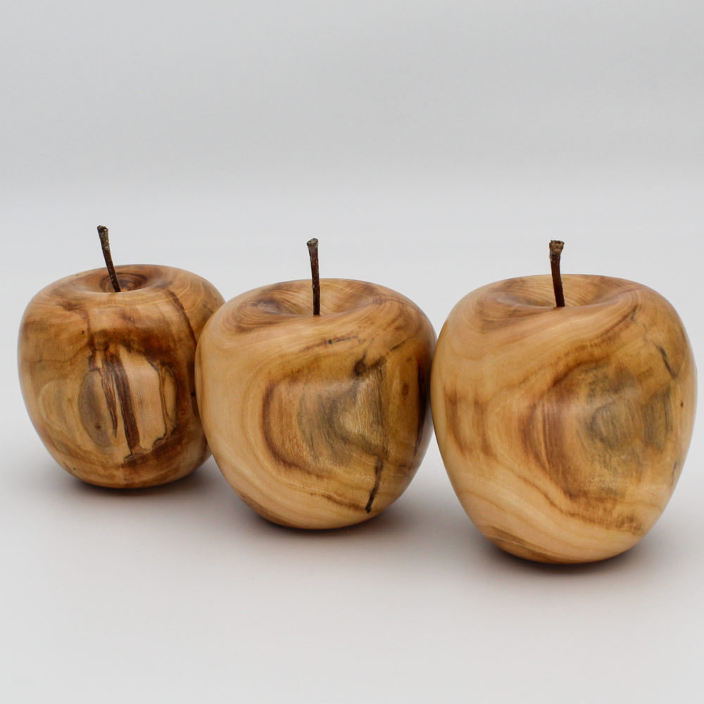 Trois pommes décoratives alignées en bois d'abricotier vue de coté