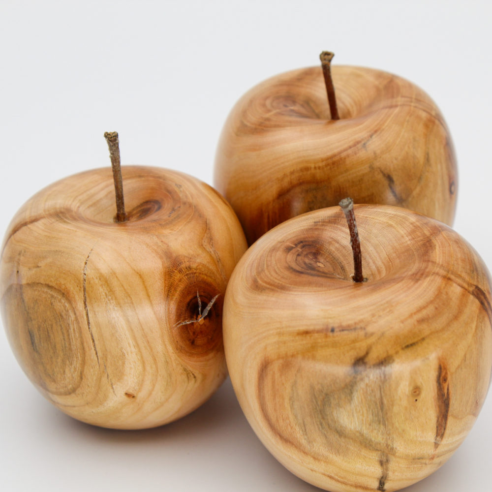 Trois pommes décoratives en bois d'abricotier vue de près et du dessus
