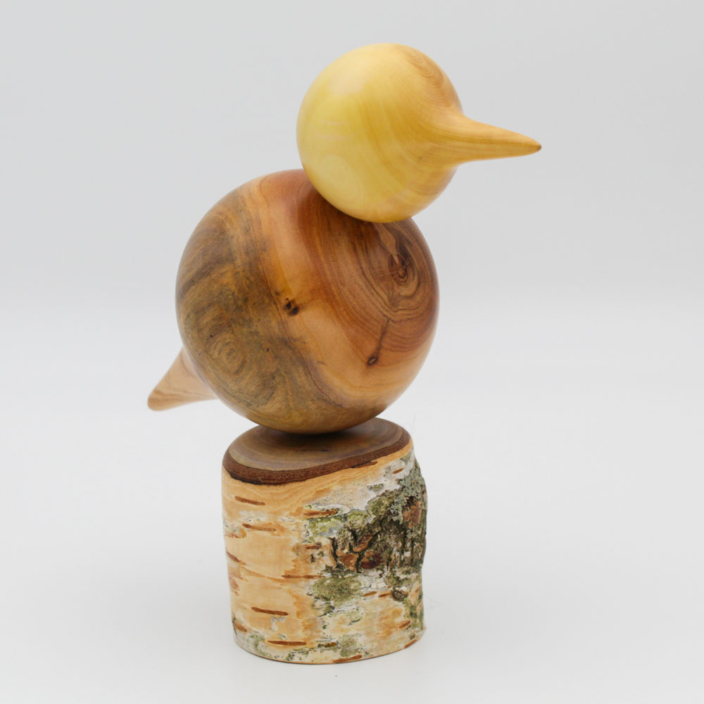 oiseau décoratif en bois perché sur un poteau en bouleau vue de trois quart