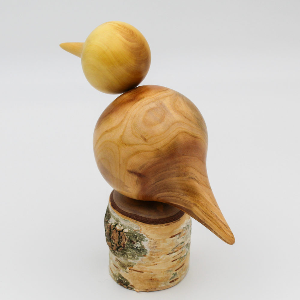 oiseau décoratif en bois perché sur un poteau en bouleau vue de dos