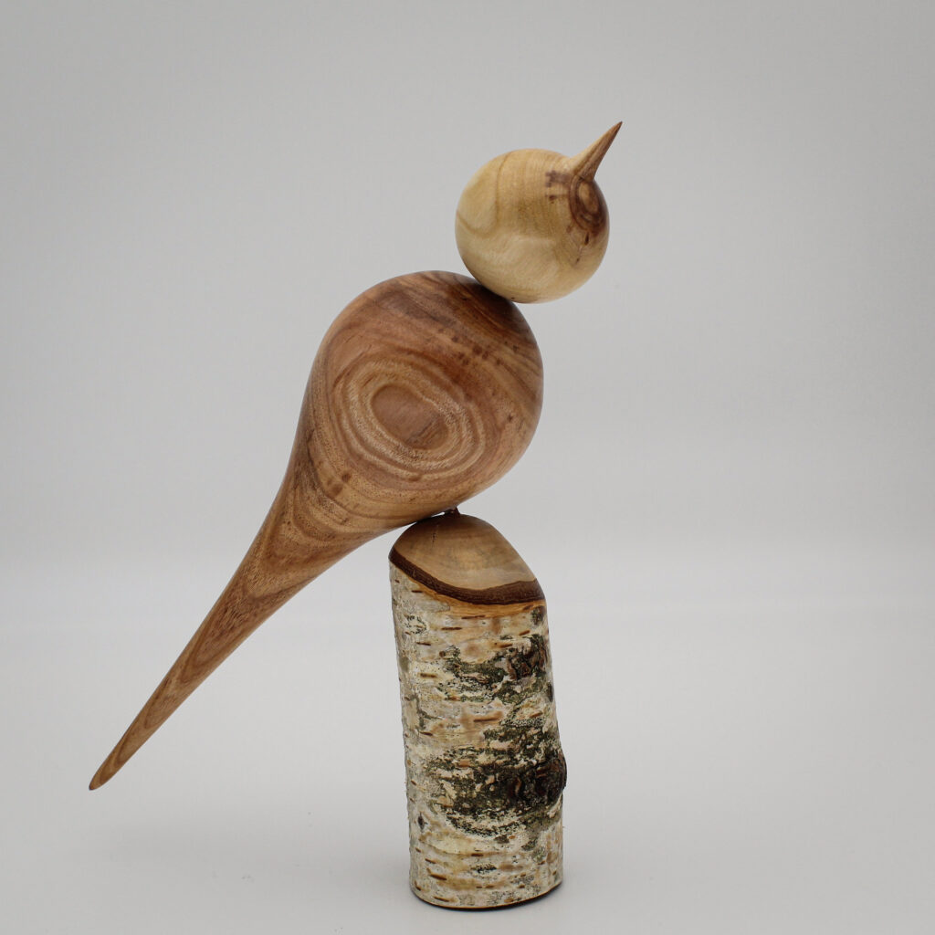 Oiseau décoratif en bois d'albizia et d'if sur son socle en bois de bouleau vue de coté