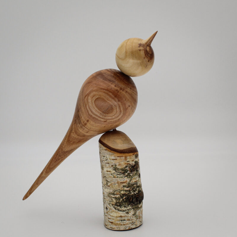 Oiseau décoratif en bois d'albizia et d'if sur son socle en bois de bouleau vue de coté